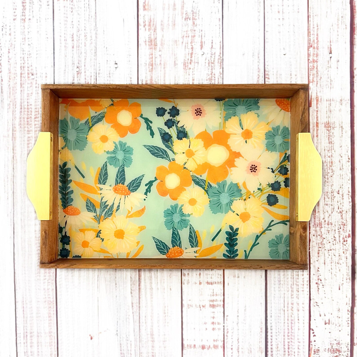 Floral-patterned tray with yellow gold handles on a wooden table
