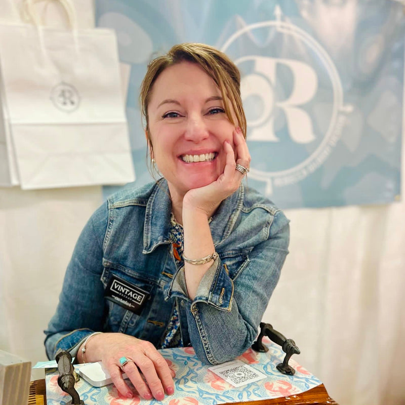 Woman in denim jacket smiling with a visible brand logo in the background. rebecca gilbert design